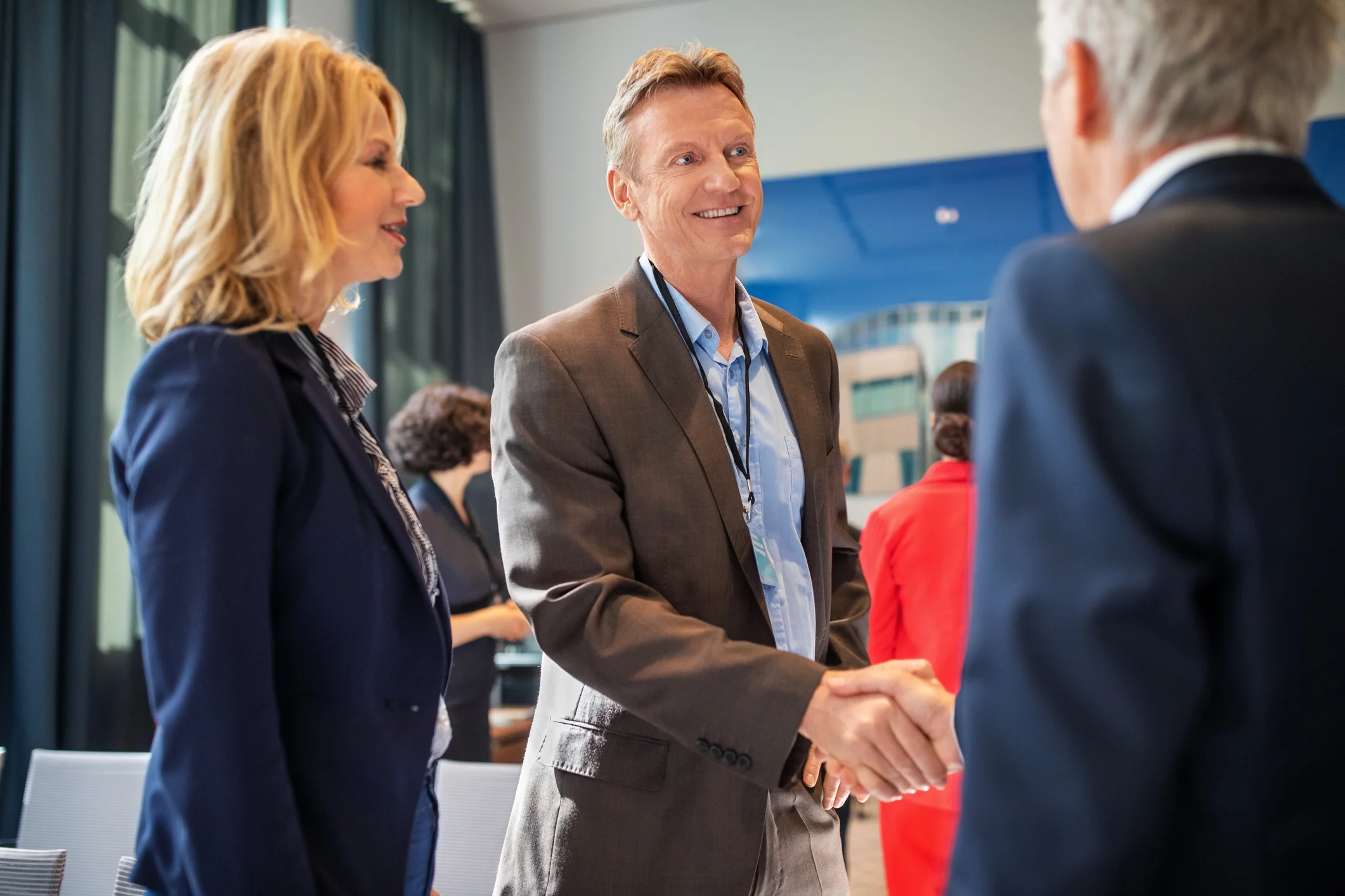 Government contractor networking event showing professionals in business attire shaking hands and building relationships at a federal industry day conference
